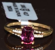 A 9k gold ring set with an oval cut Malawi garnet and eight diamonds to the shoulders, limited