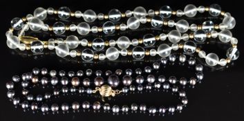 A single strand of black pearls with 14k gold clasp and a glass and gold beaded necklace with 14k