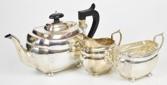 George V hallmarked silver three piece tea set of bulbous square form with incuse corners and raised