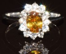 A 9k gold ring set with an oval cut sphene of approximately 0.7ct and twelve round cut diamonds, 2.