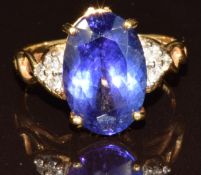 An 18k gold ring set with an oval cut AAA tanzanite of approximately 5.9ct and diamonds, with