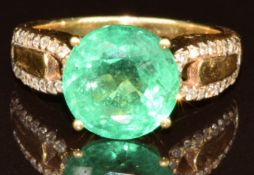 An 18k gold ring set with a round cut Ethiopian emerald of approximately 4.3ct and diamonds to the
