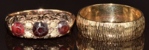 A 9ct gold wedding band/ring with textured decoration and a 9ct gold ring set with garnets and
