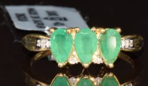 A 9k gold ring set with three pear cut Zambian emeralds totalling 0.8ct and six diamonds, with