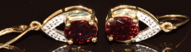 A pair of 9k gold earrings set with oval cut Malaya garnets (4.8ct) and diamonds, with