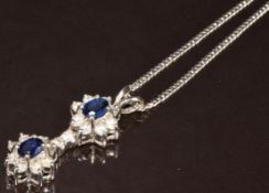 An 18ct white gold pendant set with two oval cut sapphires of approximately 0.4ct and eighteen