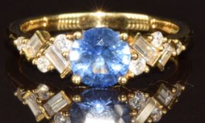 An 18ct gold ring set with a round cut sapphire of approximately 0.9ct with baguette and round cut