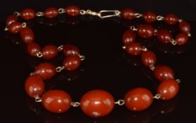 A graduated strand of cherry amber made up of twenty seven oval beads, the largest 17 x 21.7mm,