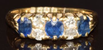An 18ct gold ring set with three cushion cut sapphires and four diamonds, London 1898, 3.6g, size M