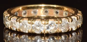 An 18ct gold eternity ring set with eighteen round brilliant cut diamonds, each approximately 0.