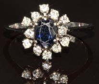 An 18ct white gold ring set with an oval cut sapphire of approximately 0.8ct surrounded by diamonds,