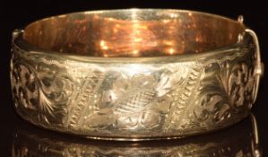 A 9ct gold bangle with engraved scrolling decoration, 27g