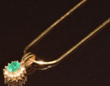 An 18k gold pendant set with an oval cut emerald of approximately 0.4ct surrounded by diamonds, on
