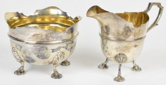 Victorian hallmarked silver sugar bowl and cream jug with shaped edges, raised on four feet,