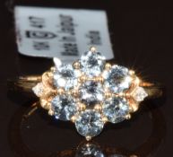 A 9k gold ring set with seven round cut Mahenge blue spinel and two diamonds in a cluster setting,