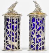 Pair of Victorian hallmarked silver peppers with pierced bodies, bird finials and blue glass liners,