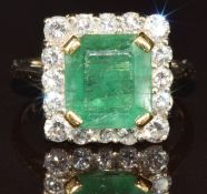 An 18ct white gold ring set with an emerald cut emerald of approximately 2.2ct surrounded by sixteen