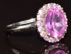 A 9ct white gold ring set with an oval cut pink sapphire surrounded by pink sapphires, 3g, size L