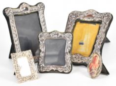 Five hallmarked silver photograph frames with embossed decoration and easel backs, the largest two