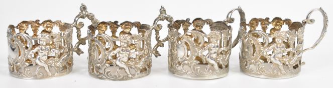 Four hallmarked silver cup or glass holders with embossed decoration of cherubs, two Sheffield 1902,