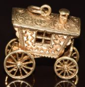 A 9ct gold charm in the form of a caravan, opening to reveal a fortune teller, 11.2g