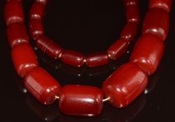 A cherry amber necklace made up of fifty two graduated barrel shaped beads, the largest 20.3 x 26mm,
