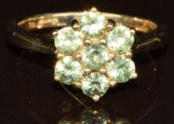 A 9k gold ring set with seven round cut demantoid garnets in a cluster, with certificate, 3.5g, size
