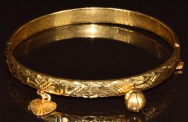 A 22ct gold bangle with two charms, 11.6g