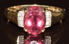 A 9k gold ring set with an oval cut pink Cuprian tourmaline of approximately 1.8ct and zircons, with