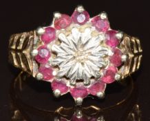 A 9ct gold ring set with a diamond surrounded by rubies, size N