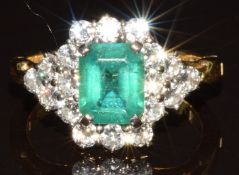 An 18ct gold ring set with an emerald cut emerald of approximately 2ct surrounded by eighteen