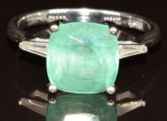 An 18k white gold ring set with a cushion cut Boyca Colombian emerald of approximately 3.8ct and two