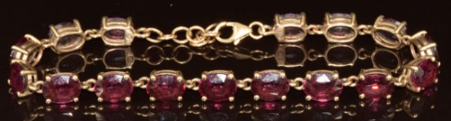 A 9k gold bracelet set with sixteen oval cut Malawi garnets, total 26ct, 12.1g, 20cm