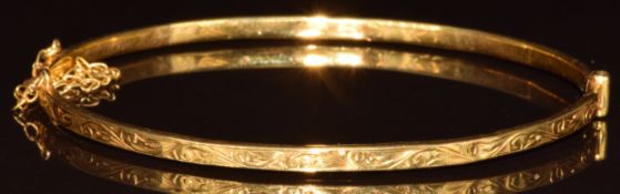 A 9ct gold bangle with engraved scrolling decoration, 3g