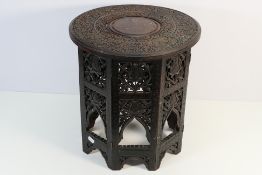 An Indian carved hardwood circular topped occasional table on folding base,