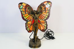 A Tiffany style, twin bulb, table lamp in the form of a standing, winged fairy,