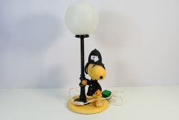 A vintage table lamp or night light in the form of Snoopy dressed as a policeman standing next to a