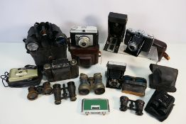 A collection of vintage binoculars, opera glasses, cameras and similar, part cased.