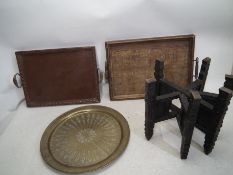 A decorative brass tray, possibly Moroccan/North African, on folding legs.