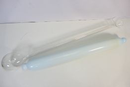 A large opaque white glass rolling pin approximately 74 cm long and a yard of ale.