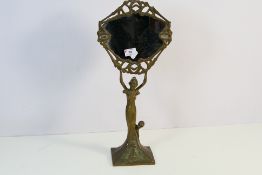 An Art Nouveau style table mirror with figural stem rising from a square section base,