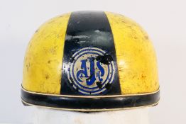 A vintage cork lined motorcycle racing helmet with AJS logo to the front.