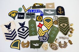 A collection of various military insignia comprising buttons, patches and badges.