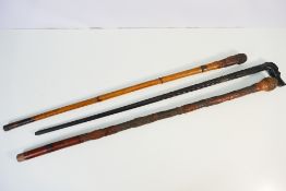 Three wooden walking sticks, one with Or