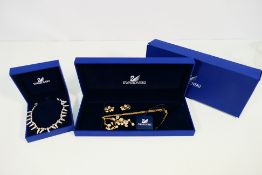 Swarovski - A boxed necklace and earrings set and a further necklace.