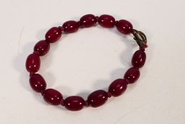 A cherry amber Bakelite bead bracelet of fourteen uniformly sized beads, approximately 1.3 cm x 0.
