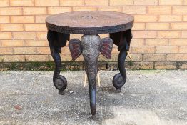 An Indian carved hardwood, circular side table on tripod elephant mask supports, 63 cm x 61 cm.