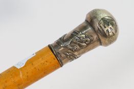 An Oriental white metal handled walking stick embossed with characters and a dragon,