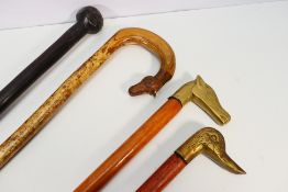 Four walking sticks / staffs, two with carved handles and two with brass animal mask handles.