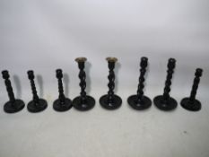 Four pairs of ebonised wooden candlesticks, two with Solomonic column stems,